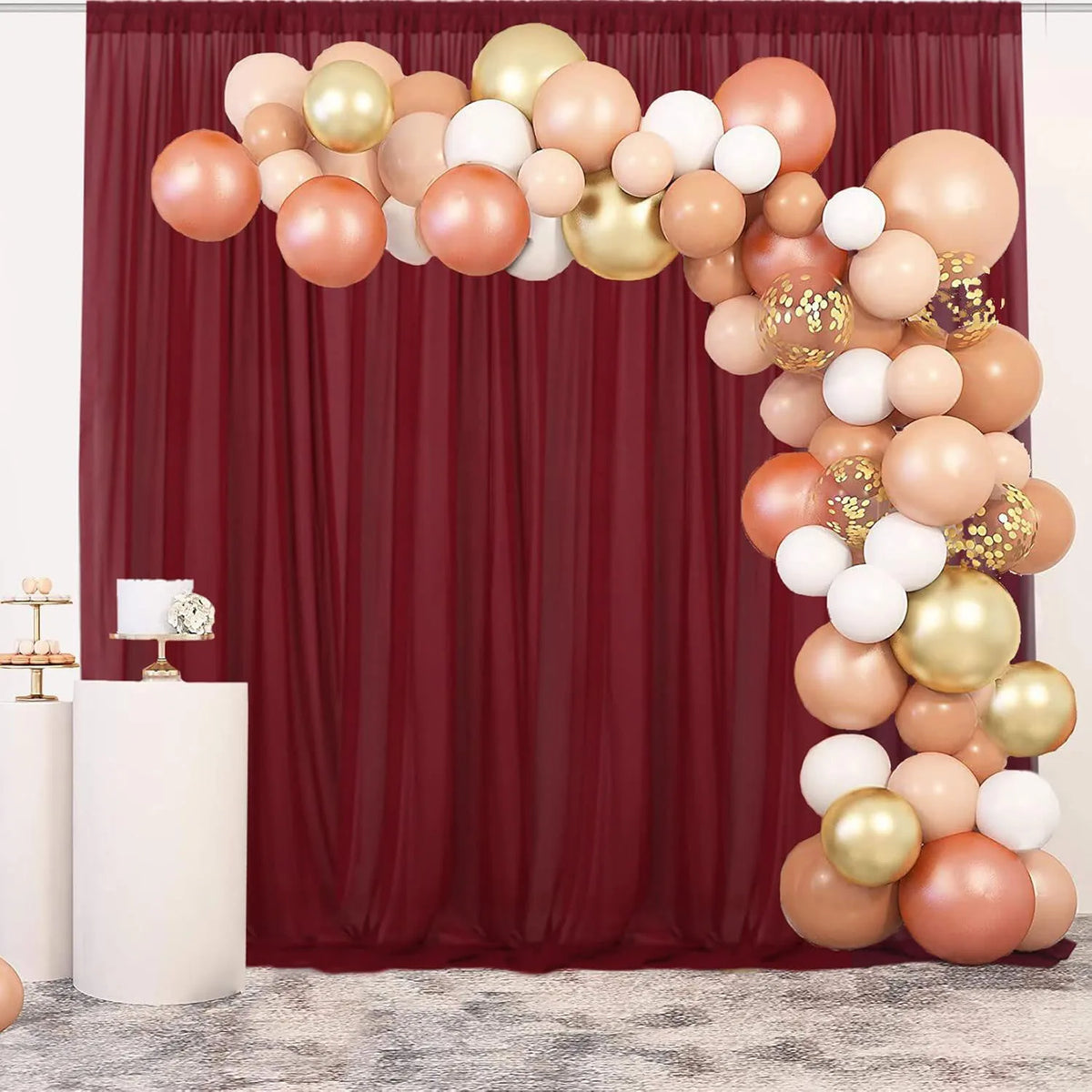 A vertical arrangement of pink, peach, and gold balloons forming a decorative curtain backdrop for an event.