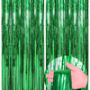 Two vertical panels of green metallic foil fringe curtains, one being held by a hand.