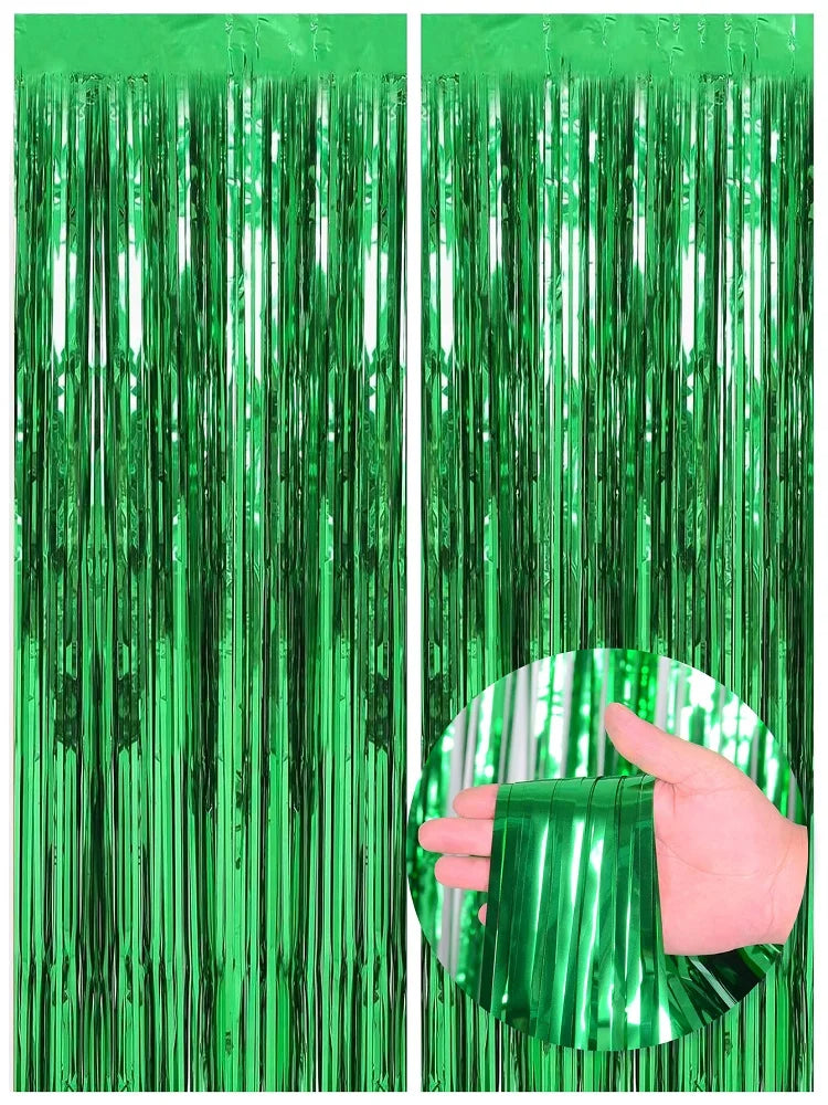 Two vertical panels of green metallic foil fringe curtains, one being held by a hand.