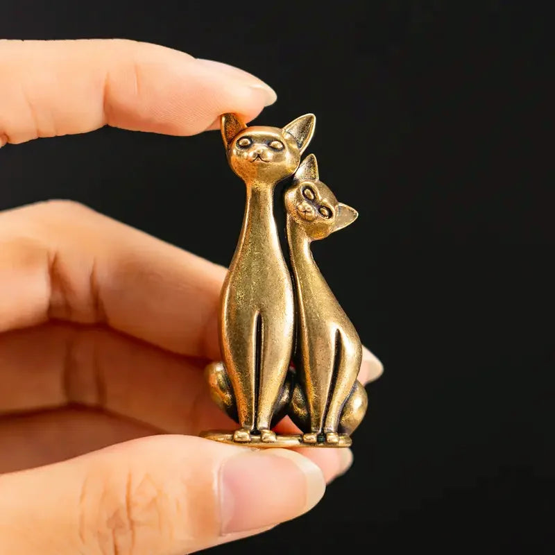 Handgefertigte Kupferstatue von zwei Katzen, die wie Eulen aussehen, in der Hand einer Person gehalten.