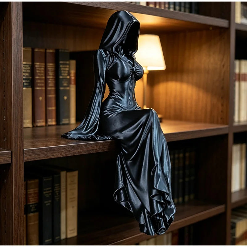 A black, flowing gown figurine of a hooded figure sitting on a wooden shelf among books.