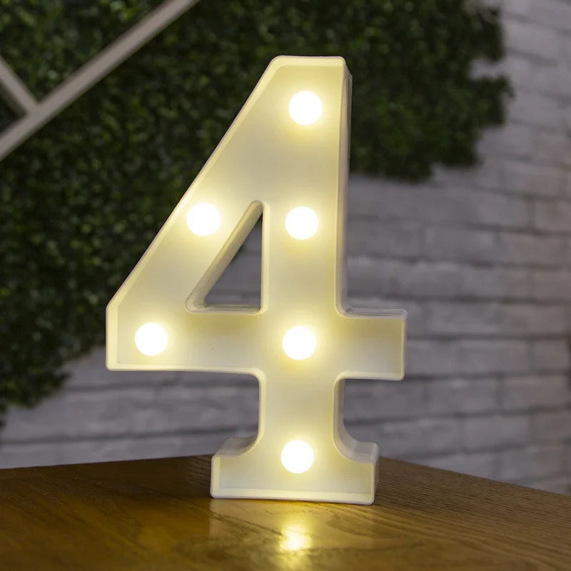 A glowing warm white LED alphabet letter light shaped like the number four resting on a wooden surface.
