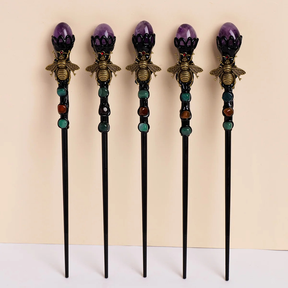A set of four amethyst bee crystal scepters with gold accents and colored beads.