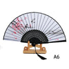 A folding hand fan with a black and white striped paper and pink floral design.