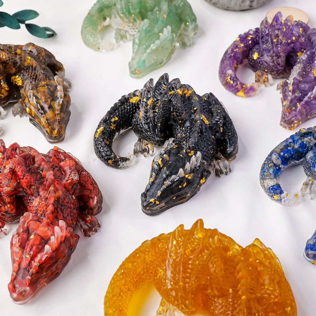 A collection of natural crystal dragon figurines in various colors including green, purple, black, red, and orange.