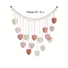 Handwoven pink leaf tassels hanging from a string, used as a decorative wall hanging.