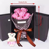 A gift box containing a pink rose bouquet and a white plush bear, tied with a satin ribbon.