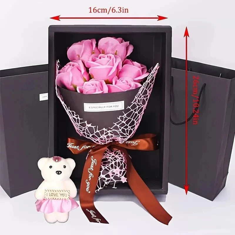 A gift box containing a pink rose bouquet and a white plush bear, tied with a satin ribbon.
