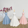 A white silicone mold shaped like a wedding dress is displayed next to pink and blue candles.
