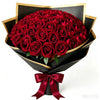 A bouquet of 50 deep red velvet artificial roses wrapped in black paper and tied with a satin ribbon.