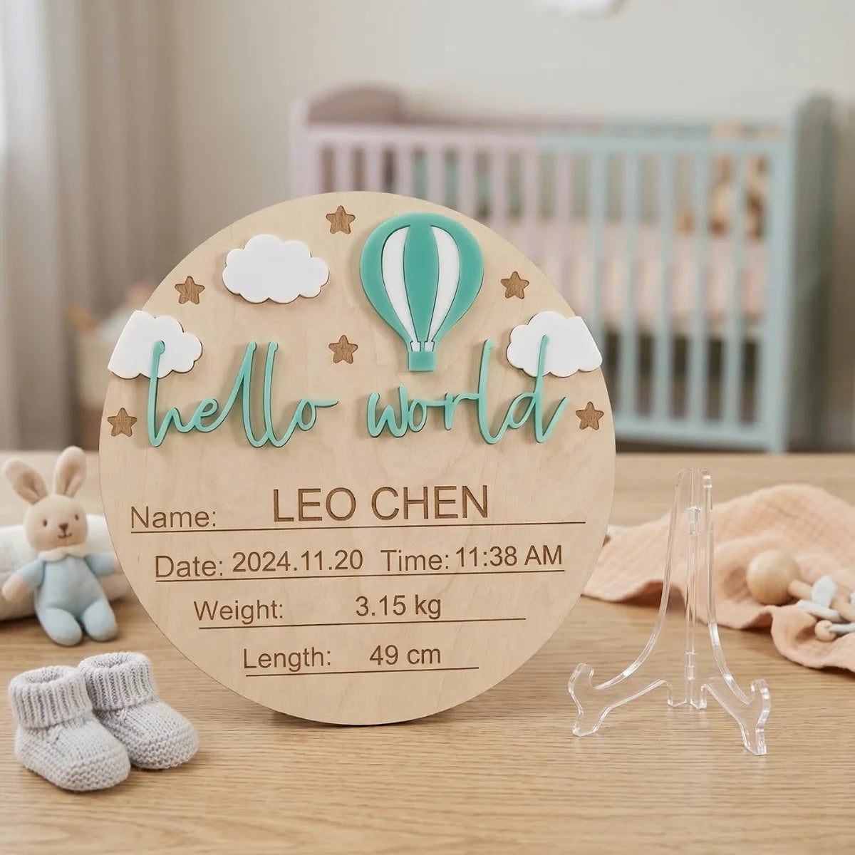 A natural wood birth announcement plaque shaped like a hot air balloon with the text Hello World and baby details