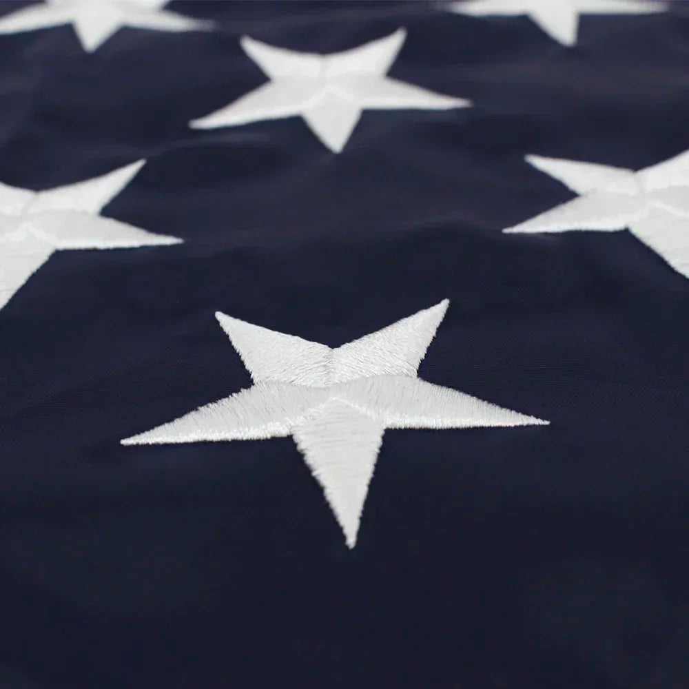 A close-up of a dark blue fabric featuring white embroidered stars in the pattern of an American flag.