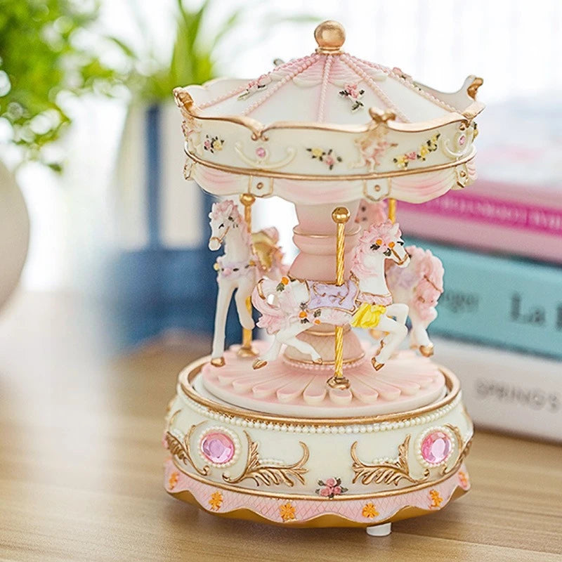 A delicate pink and cream resin carousel music box with a dome top and horses.