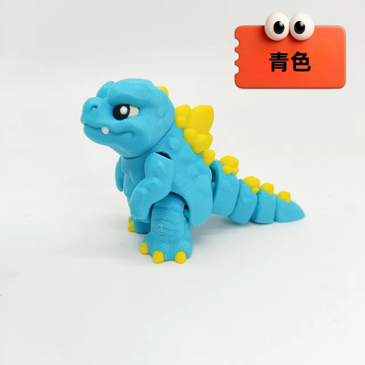A blue 3D printed Godzilla sitting figure with yellow accents, displayed next to an orange color swatch.