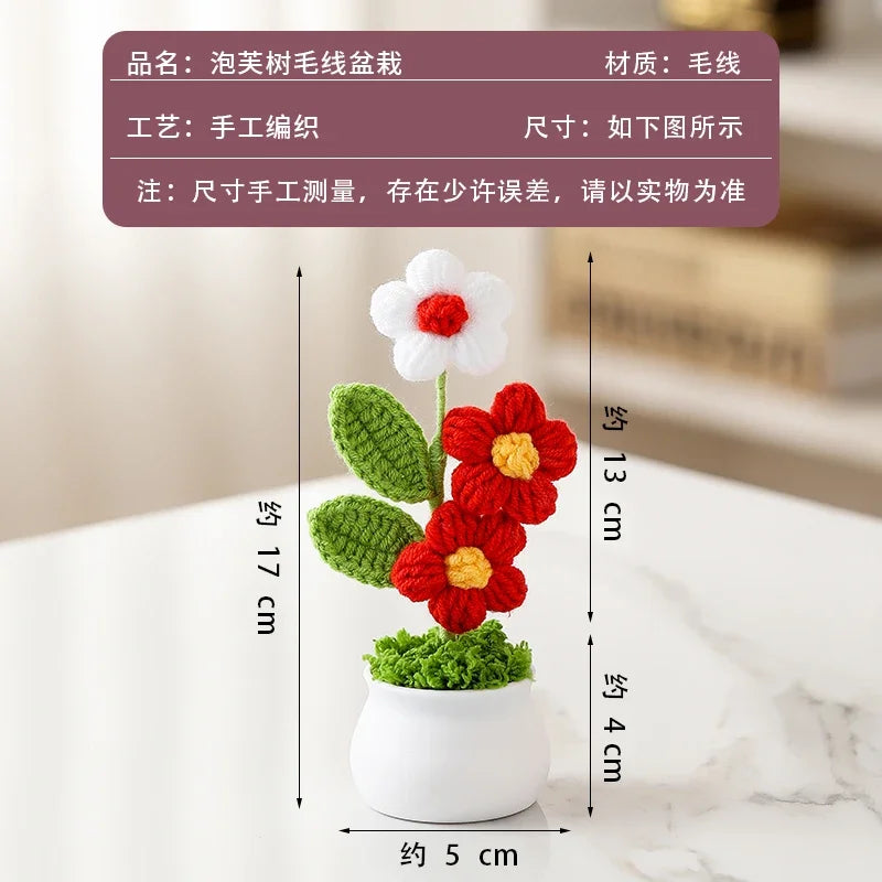 A hand-woven crochet flower in red and white, potted in a white ceramic container.