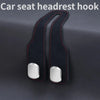 A black car seat headrest hook with an alloy core and stitching, shown against a dark background.
