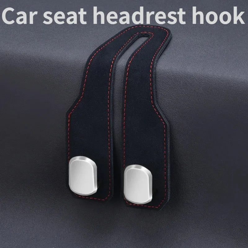 A black car seat headrest hook with an alloy core and stitching, shown against a dark background.