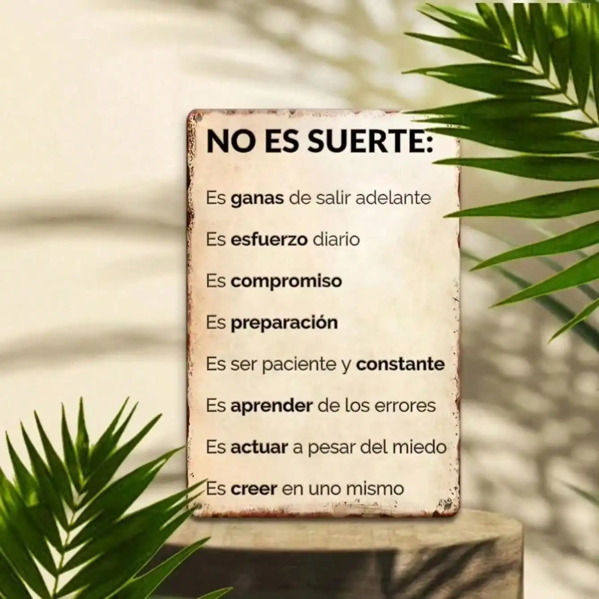 A rustic metal wall sign with text on it is displayed in a natural, leafy setting.