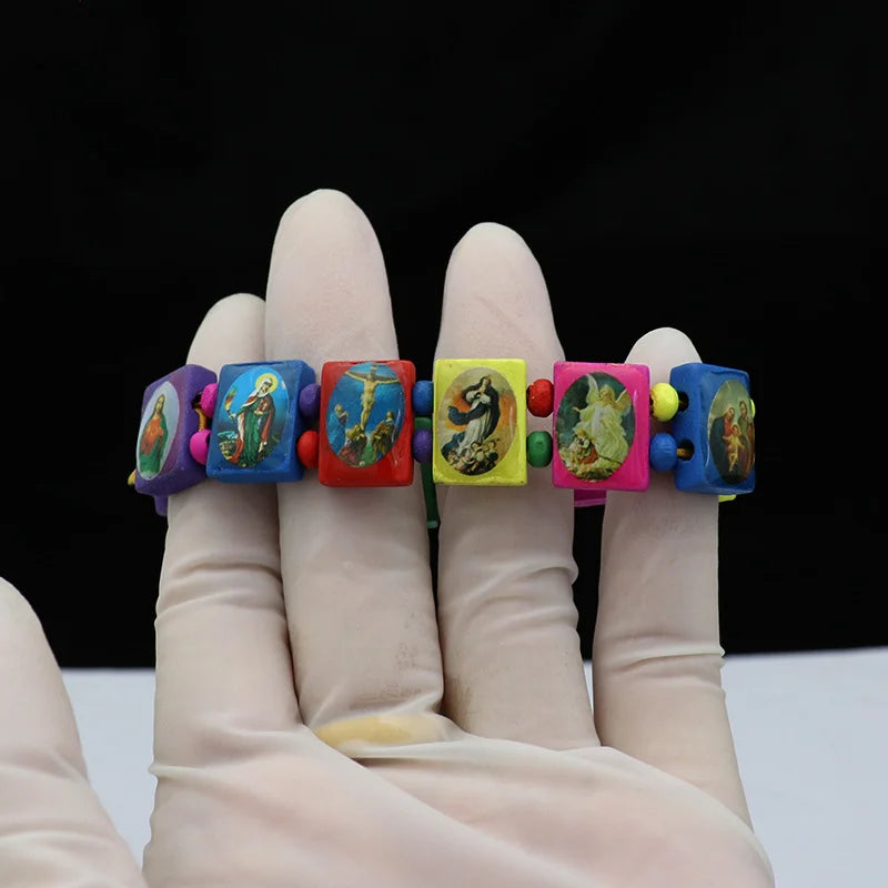 A hand wearing a natural wooden rosary bracelet with Virgin Mary and Jesus charms.