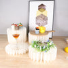 A folding dessert table display featuring cupcakes and a cake on tiered stands with geometric decor.