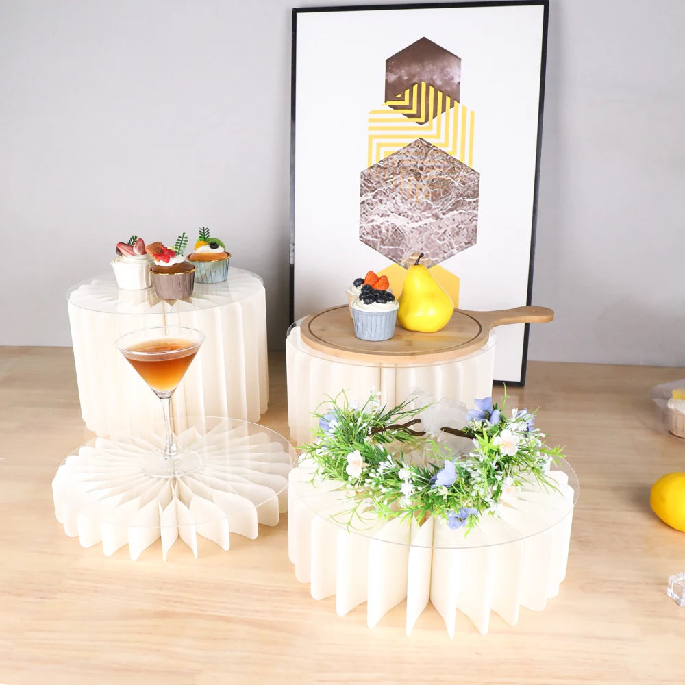 A folding dessert table display featuring cupcakes and a cake on tiered stands with geometric decor.