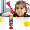 A young girl holds a red air pressure horn for sports events on a white table.