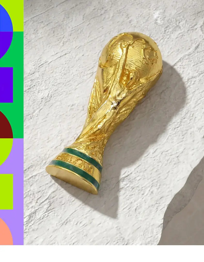 Gold FIFA 2026 World Cup Trophy fridge magnet with a green band.