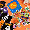 A collection of Halloween stationery including trick-or-treat bags, stickers, and themed paper crafts on an orange background