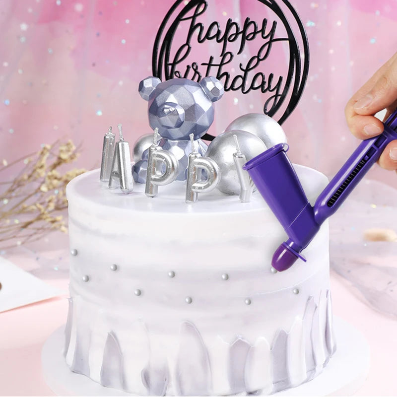 A white cake decorated with silver and purple pearl ball applicators and a bear topper.