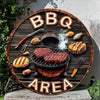 Panneau en bois rond avec les lettres BBQ AREA gravées, présentant une poêle à griller et des ustensiles.