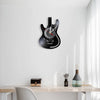 A vintage vinyl record guitar wall clock mounted on a white wall above a wooden table.