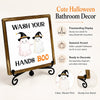 A wooden sign featuring two Halloween ghost figures with witch hats, designed for bathroom decor.