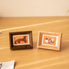 Two wooden photo frames display small images, one featuring a leopard print and the other showing children.