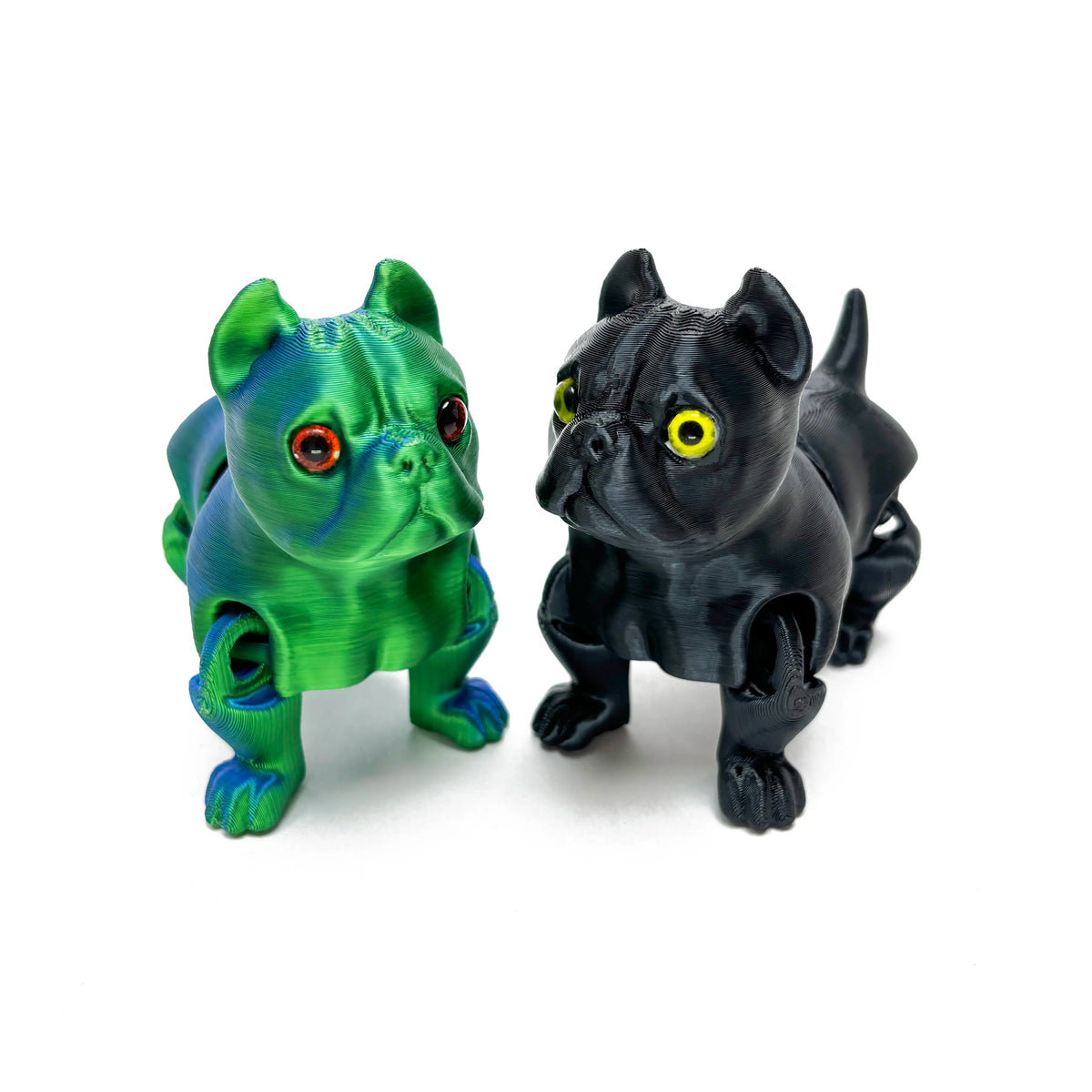 A pair of 3D printed articulated bulldog figurines, one green and one black, displayed against a white background.