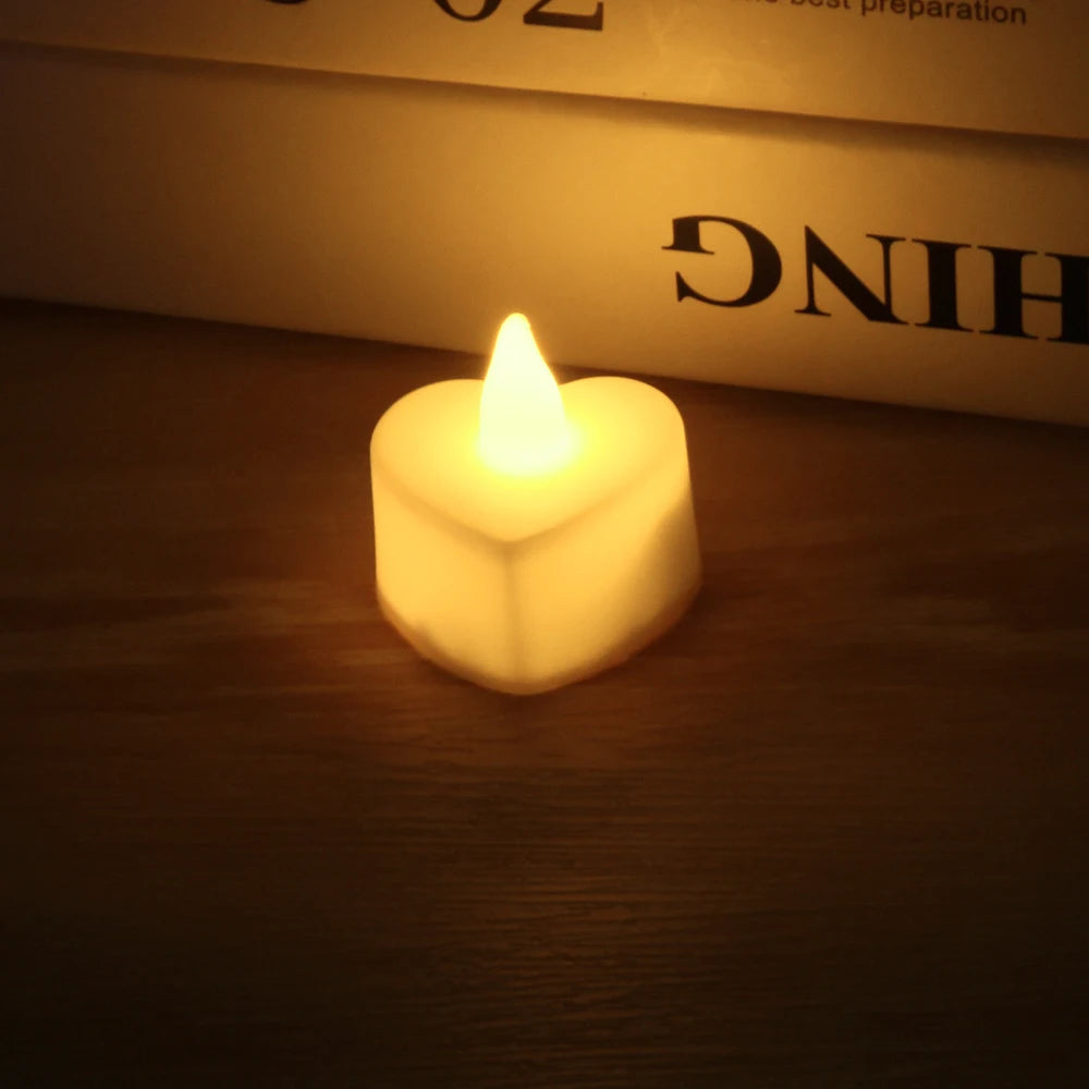 A glowing white heart-shaped tealight candle resting on a wooden surface with blurred text in the background.