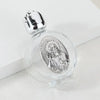 A clear glass bottle with a silver figurine inside and a twist cap, resting on a white surface.
