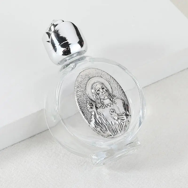 A clear glass bottle with a silver figurine inside and a twist cap, resting on a white surface.