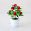 Artificial lemon tree bonsai with bright red fruit on a green branch planted in a white pot