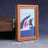 A wooden photo frame displaying a watercolor-style cat portrait on blue and purple background.