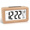 A light wood digital alarm clock displaying the time 12:22, AM, with a calendar date and temperature reading.