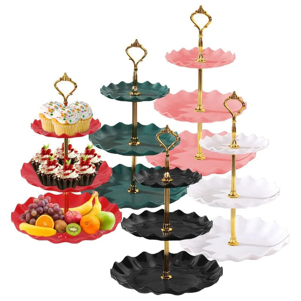 Soporte de postres de plástico de tres niveles con platos rosas y verdes, lleno de cupcakes y dulces.