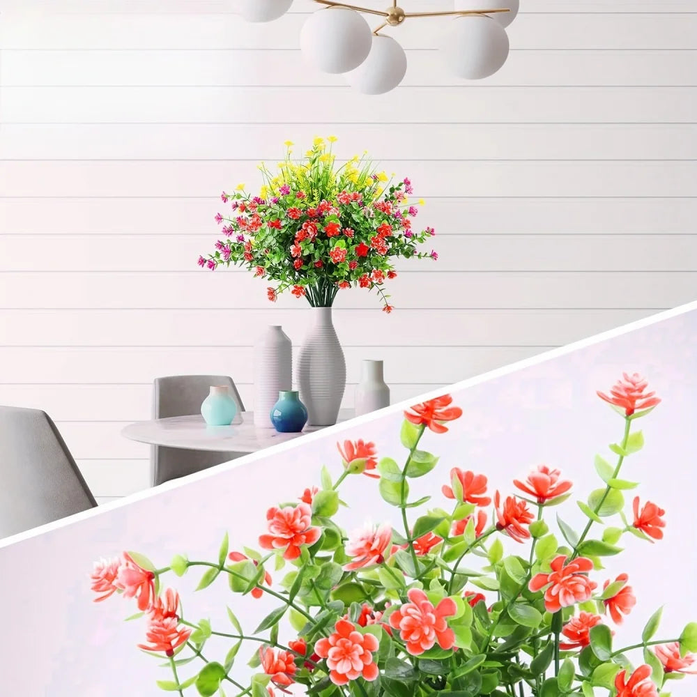 A vibrant bouquet of artificial flowers in various shades of red, pink, and yellow displayed against a white wooden backgroun