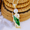 A gold-plated Saint Jude pendant necklace featuring a figure in green drapery and a halo, resting on woven mats.