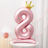 Pink aluminum foil number balloons shaped like the number eight with a gold crown topper
