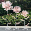 A set of three large pink velvet mesh flowers on white stems used for wedding decoration.