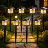 Eight solar powered LED pathway lights illuminating a stone path at dusk.
