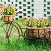 A vintage bicycle is decorated with potted artificial calla lily bouquets in a garden setting.