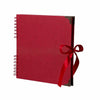 Bloc-notes photo rouge à plat avec reliure spirale et ruban rouge autour de la couverture.