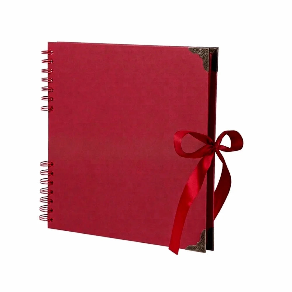 Bloc-notes photo rouge à plat avec reliure spirale et ruban rouge autour de la couverture.