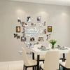 A wall collage featuring framed photos and leaves arranged in the shape of a family tree for a decorative display.